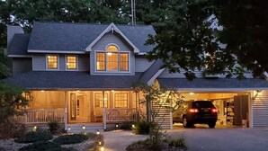 Une maison à deux étages avec un garage, une véranda et une allée.