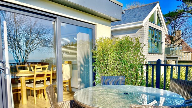 A glass-enclosed patio with wicker furniture, a round glass table, and a view of the sea. - 16 Beatrice Avenue, Shanklin, isle of Wight (Shanklin)