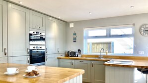 A modern kitchen with grey cabinets, a wooden countertop, a built-in oven, a toaster, and a window with blinds. - 16 Beatrice Avenue, Shanklin, isle of Wight (Shanklin)