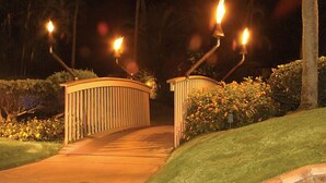 A gated pathway with a curved railing, surrounded by well-maintained hedges and flowering plants. - Pono Kai Resort - 1 Bedroom (Kapaa)