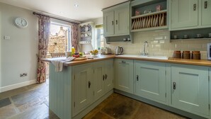 Cozinha com armários azul claro, painel de backsplash de pedra e janela com cortinas.