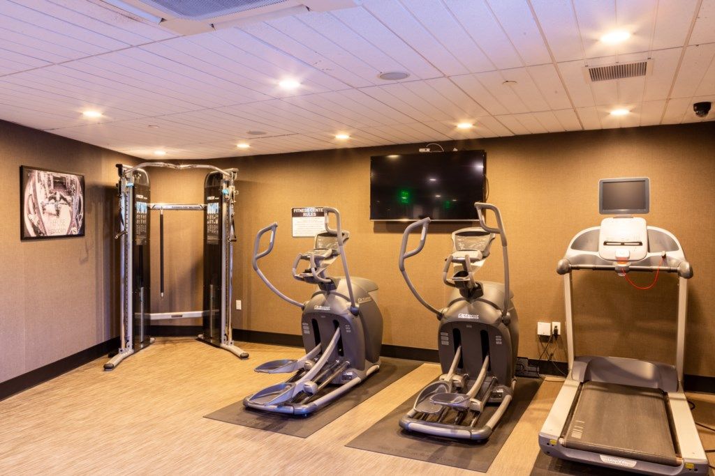 Un gimnasio con cintas de correr, elípticas y máquinas de pesas.