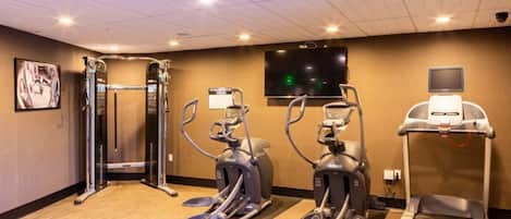 Un gimnasio con cintas de correr, elípticas y máquinas de pesas.