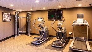Un gimnasio con cintas de correr, elípticas y máquinas de pesas.