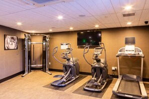 Un centre de remise en forme équipé de tapis de course, de vélos elliptiques et d'une machine de musculation.