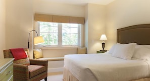 Een hotelkamer met een bed, een stoel, een raam en een lamp.