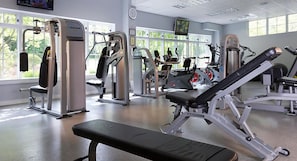 A gym with Nautilus equipment, large windows, and a television.