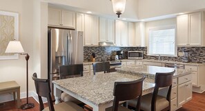 A modern kitchen with granite countertops, stainless steel appliances, and white cabinetry.