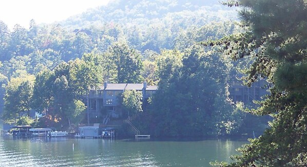 A lakeside property with docked boats, a building with a dock, and dense forest in the background.