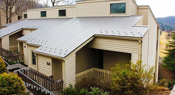 A row of single-story mobile homes with a metal roof, wooden railings, and a small porch area.