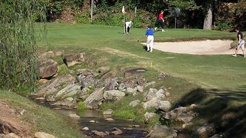 Un parcours de golf avec un ruisseau, des rochers et des bunkers de sable.