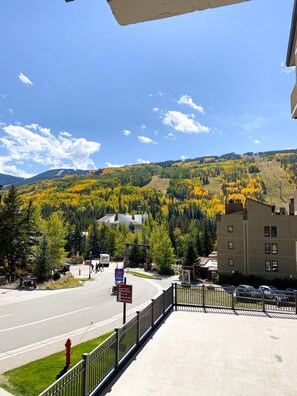 Hotel com vista para paisagem montanhosa, área de estacionamento e placa indicando disponibilidade de estacionamento por hora.