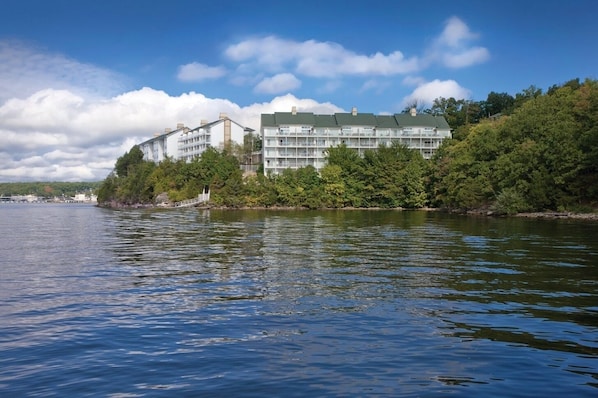A waterfront hotel with multiple floors, a green roof, and a view of the water.