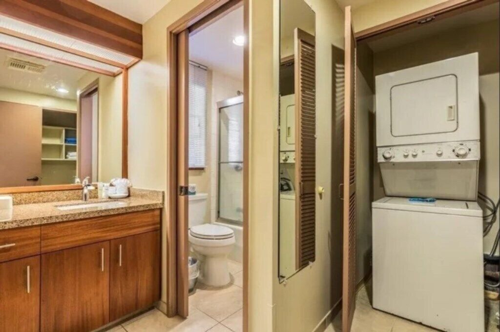 A bathroom with a wooden vanity, a toilet, and a washing machine.