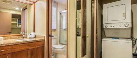 A bathroom with a wooden vanity, a toilet, and a washing machine.