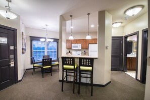 A compact kitchen with a microwave, refrigerator, and bar stools.