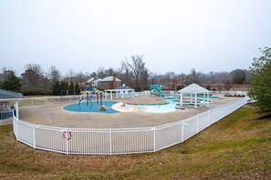 Un espacio exterior cercado con piscina, un cenador y un parque infantil.