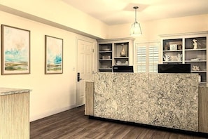 A kitchen with a marble countertop, wooden cabinets, and a hanging light fixture.
