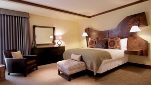 Une chambre d’hôtel avec un grand lit, une chaise, une commode et un miroir.