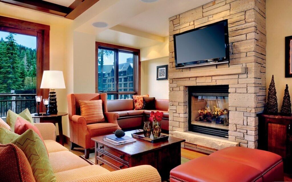 A cozy living room with a fireplace, comfortable seating, and a large window offering a view of the outdoors.