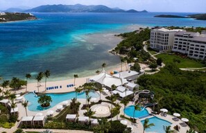 Un complexe hôtelier doté de plusieurs piscines, d’une plage et d’un grand bâtiment.