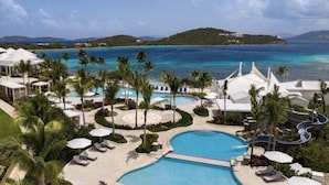 A resort with a large swimming pool, palm trees, and a view of the ocean. - Ritz Carlton Club, St Thomas - 3 Bedroom (St. Thomas)