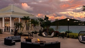 An outdoor seating area with sofas and tables, a fire pit, and a view of the sea. - Ritz Carlton Club, St Thomas - 3 Bedroom (St. Thomas)