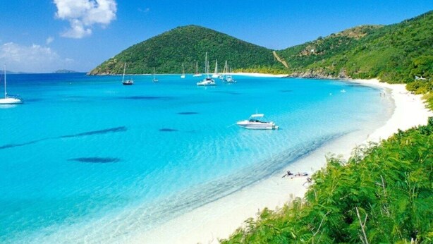 A beach with clear turquoise waters, boats, and a hilly backdrop. - Ritz Carlton Club, St Thomas - 3 Bedroom (St. Thomas)
