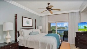 A bedroom with a large bed, a ceiling fan, a TV, and a balcony with a view of the landscape. - Ritz Carlton Club, St Thomas - 3 Bedroom (St. Thomas)
