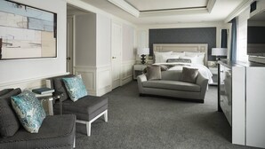 Une chambre d’hôtel avec un lit, un canapé, une chaise, un bureau et un grand tableau au mur.