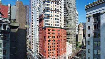 A high-rise building with a red corner section, surrounded by taller buildings.