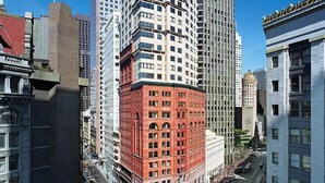 Un immeuble de grande hauteur, avec une partie d’angle rouge, entouré d’immeubles encore plus hauts.
