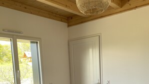 Ett sovrum med en säng, en dörr, ett fönster och en taklampa.