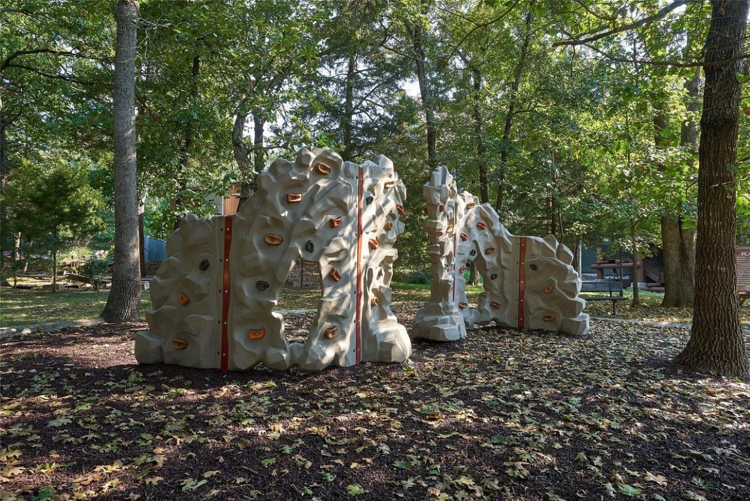 Una instalación escultórica en un parque con árboles y bancos al fondo.