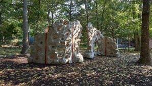 Une installation de sculptures dans un parc, avec des arbres et des bancs en arrière-plan.