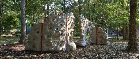 Una instalación escultórica en un parque con árboles y bancos al fondo.