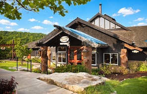 Un chalet doté d’une façade en pierre, de grandes fenêtres et d’un porche abrité.