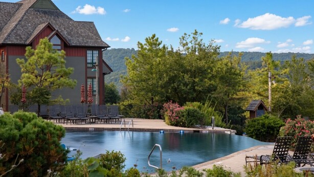 Une piscine avec des chaises longues et un bâtiment à l’extérieur rouge et doté d’un toit en pente.