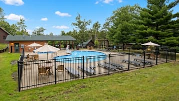 A backyard with a swimming pool, lounge chairs, and a fenced area.