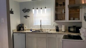 A kitchen with white cabinets, a built-in dishwasher, a microwave, and a coffee maker. - Relaxing condo getaway (Huntsville)