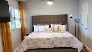 A bedroom with a bed, a ceiling fan, a window with curtains, and a white rug. - Relaxing condo getaway (Huntsville)