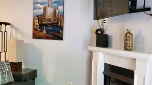 A living room with a fireplace, a mounted TV, and a cityscape poster on the wall. - Relaxing condo getaway (Huntsville)