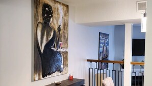 A living room with a large abstract painting, a dark wooden console table, a glass coffee table, and a light-colored armchair. - Relaxing condo getaway (Huntsville)