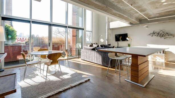 A spacious living area with a large window, a sofa, a dining table, and a kitchen island. - Spacious Chic 1Br East Nashville Loft! (Nashville)