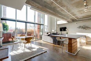 A spacious living area with a large window, a sofa, a dining table, and a kitchen island. - Spacious Chic 1Br East Nashville Loft! (Nashville)
