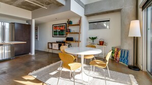 A modern kitchen with stainless steel appliances, a dining area with a round table and chairs, and a large window providing natural light. - Spacious Chic 1Br East Nashville Loft! (Nashville)