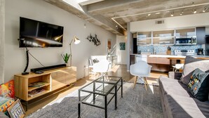 A modern living space with a flat-screen TV, wooden entertainment unit, glass coffee table, and a cozy seating area. - Spacious Chic 1Br East Nashville Loft! (Nashville)