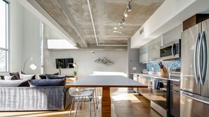 A modern kitchen with stainless steel appliances, a large island, and a dining area with a sofa and chairs. - Spacious Chic 1Br East Nashville Loft! (Nashville)