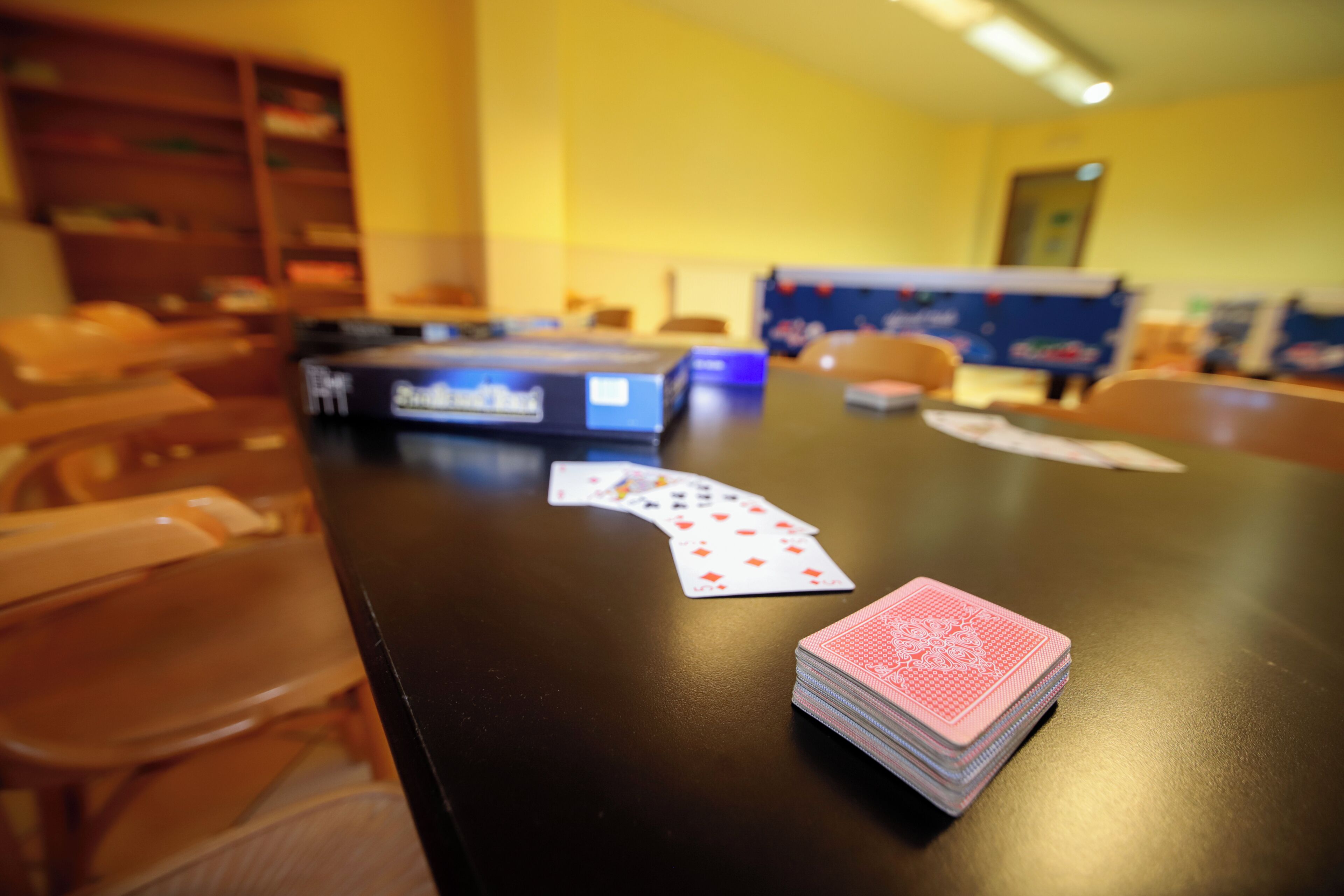 A room with a wooden table displaying playing cards and a blue box, likely a poker table.