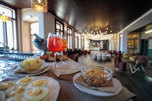 Un comedor con una mesa dispuesta para una comida, que incluye platos de comida, un cuenco de nueces y un vaso de bebida roja.